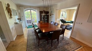 A dining room with a wooden table, chairs, a patterned rug, and a view of the outdoors. - Vacation home with 3 separate bedrooms, 160 square meters (Truchtlaching)