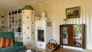 A living room with a fireplace, a green sofa, a wooden coffee table, and a bookshelf. - Vacation home with 3 separate bedrooms, 160 square meters (Truchtlaching)