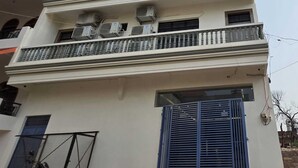 Een meerlaags gebouw met balkons, airconditioning en een blauw hek.