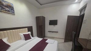 Een hotelkamer met een groot bed, een aan de muur bevestigde televisie en een kledingkast.
