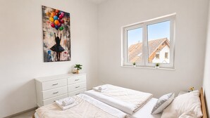 Een slaapkamer met twee bedden, een kaptafel, een raam met uitzicht en een schilderij aan de muur.