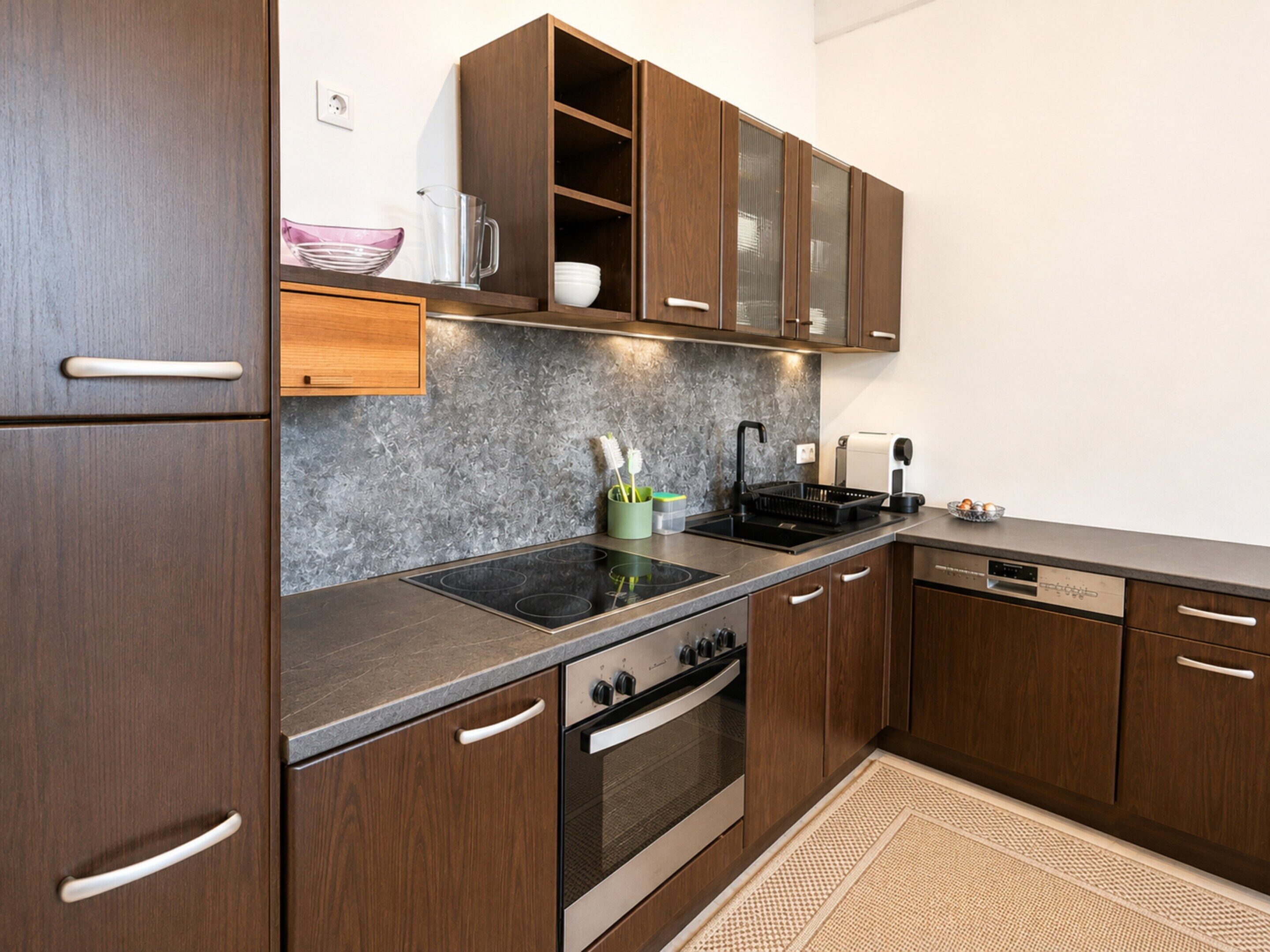 A modern kitchen with wooden cabinets, a built-in oven, a stovetop, and a dishwasher.
