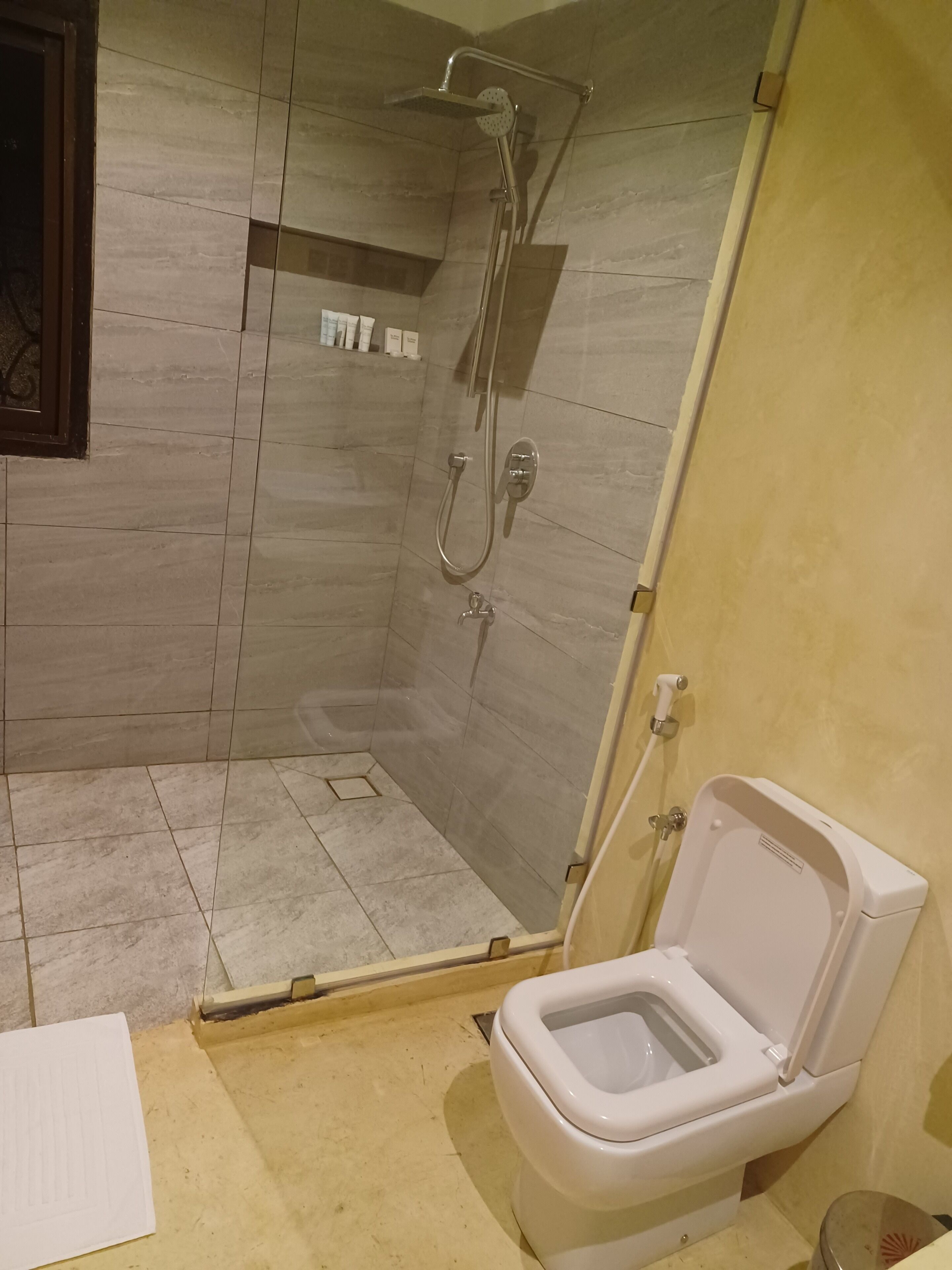 A bathroom with a shower, toilet, and tiled walls.