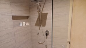 En dusch med ett handhållet duschmunstycke, ett väggmonterat duschmunstycke och en kontrollpanel.