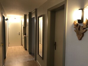 A hallway with doors, a light fixture, and a wall-mounted decoration. - Alkazar Wg. 11 Appartement/Fewo, Bad, WC, 6-Bettwohnung by Interhome (Arosa)