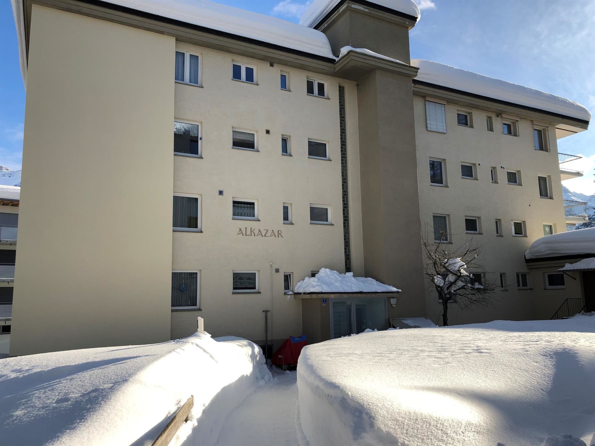 A multi-story building with the name 'ALKAZAR' on the facade, surrounded by snow.