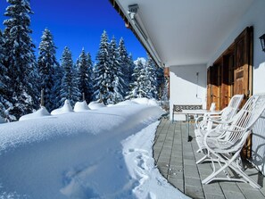 Paisagem coberta de neve com um edifício e um pátio com mesas ao ar livre.