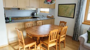 Een keuken met houten kastjes, een granieten aanrecht en een eettafel met stoelen.