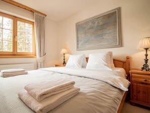 A neatly made bed with white linens and folded towels, a painting on the wall, and two bedside lamps. - Chesigna 2 Appartement/Fewo, Bad, WC, 6-Bettwohnung Chesigna 2 by Interhome (Arosa)