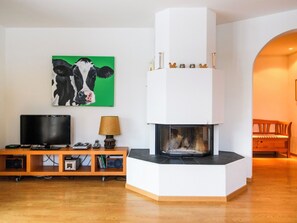 Ein modernes Wohnzimmer mit Kamin, Fernseher und einem Bild von einer Kuh.