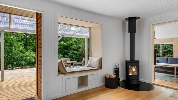A modern interior with a built-in fireplace, wooden flooring, and large windows offering a view of the outdoors. - "Hejne" - 600m from the sea by Interhome (Glesborg)