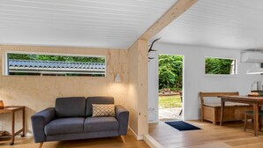 A modern interior with a sofa, wooden flooring, and a view of the outdoors. - "Hejne" - 600m from the sea by Interhome (Glesborg)