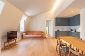 Eine moderne Wohnung mit Wohnzimmer, Sofa, Esstisch und Küchenbereich.