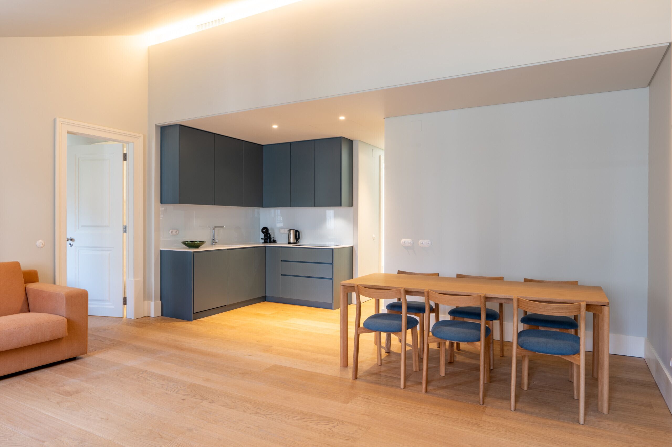 A modern apartment with a kitchen, dining area, and a sofa.
