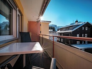 Ein Balkon mit Tisch und Stühlen, mit Blick auf einen Berg und Gebäude.