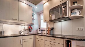 Una cocina moderna con electrodomésticos de acero inoxidable, encimera de granito y armarios color beige.