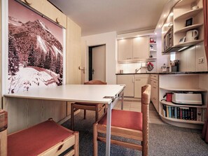 Eine kompakte Küche mit Essbereich, einem Bücherregal und einer Tür zu einem weiteren Zimmer.