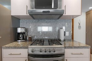 A kitchen with a gas stove, a coffee maker, and a microwave. - Vista La Jolla 406A | 1BR Near Costa Azul (San José del Cabo)