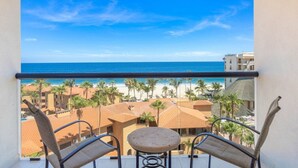 A balcony with a view of the beach, palm trees, and buildings. - Vista La Jolla 408B | King Suite Minutes from Costa Azul Beach (San José del Cabo)