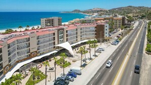 A coastal hotel with a beachfront view, multiple parking levels, and a prominent white architectural feature. - Vista La Jolla 408B | King Suite Minutes from Costa Azul Beach (San José del Cabo)