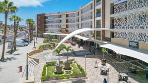 A modern hotel with a central courtyard, outdoor seating, and a prominent sign for Condos for Sale. - Bright and comfortable lock-off suite in Vista La Jolla featuring a king bed, private entrance, full bathroom, mini-fridge, microwave, coffee station, and high-speed Wi-Fi. Just minutes from Costa Azul Beach, dining, shopping, golf, and downtown SJC. (San José del Cabo)