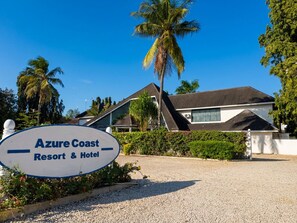 Azure Coast Resort & Hotel with a signboard, palm trees, and a building with a tiled roof. - Azure Coast Resort Hotel (Dar es Salaam)