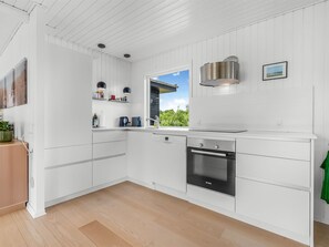 A modern kitchen with white cabinetry, a Bosch oven, and a window with a view of greenery. - "Tabetha" - 800m from the sea by Interhome (Knebel)