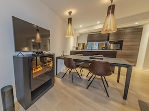 Eine moderne Küche mit Essbereich, einem Flachbildfernseher und einem Kamin.