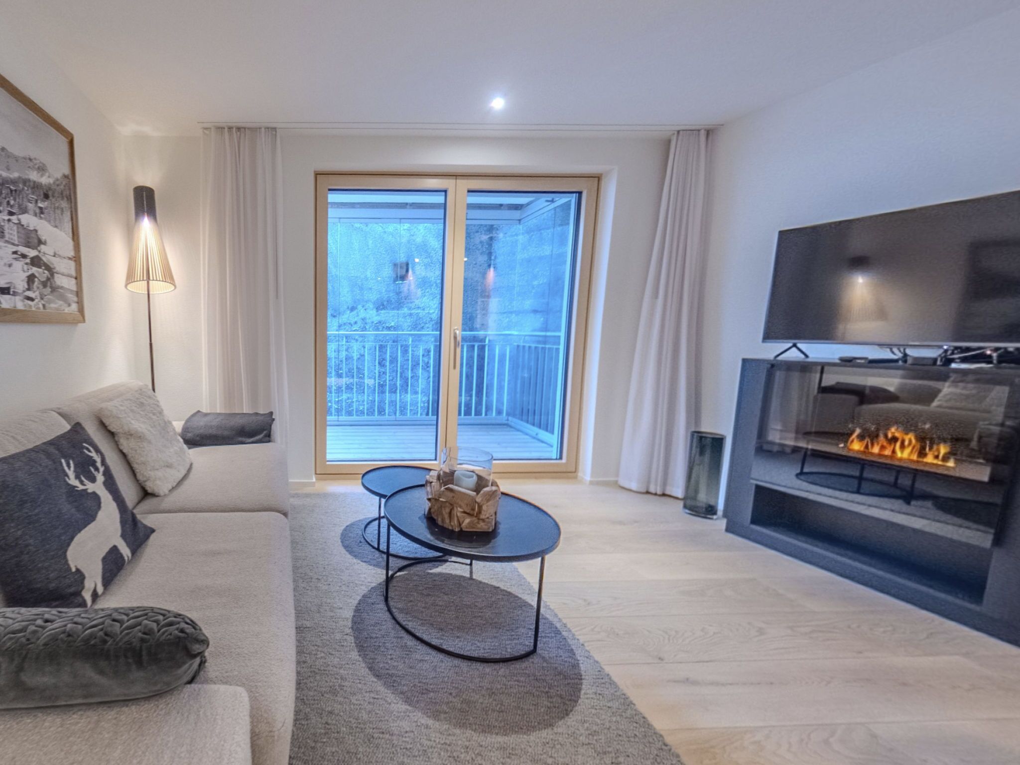 Un salon moderne comprenant un canapé, une table basse, une cheminée et une grande fenêtre donnant sur l’extérieur.