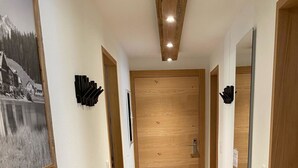Ein Korridor mit Holzboden, schwarzem Teppich, einer Holztür und einem gerahmten Bild an der Wand.