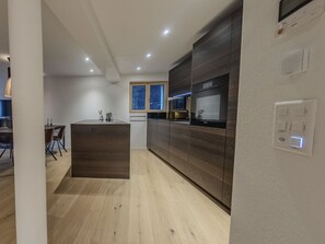 A modern kitchen with wooden cabinets, a central island, and a dining area with chairs. - Koller Sapuen by Arosa Holiday Appartement/Fewo, Dusche, WC, 3-Bettwohnung by Interhome (Arosa)