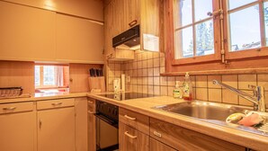 Une cuisine avec des meubles en bois, un évier en acier inoxydable et une fenêtre donnant sur les arbres.