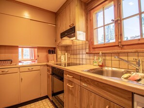 A kitchen with wooden cabinets, a stainless steel sink, and a window with a view of trees. - Chalet Soldanella by Arosa Holiday Appartement/Fewo, Dusche oder Bad, WC, 9-Bett by Interhome (Arosa)