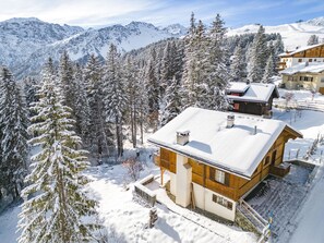 A wooden chalet with a snow-covered roof, surrounded by snow-laden trees and mountains in the background. - Chalet Soldanella by Arosa Holiday Appartement/Fewo, Dusche oder Bad, WC, 9-Bett by Interhome (Arosa)