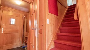Un intérieur en bois avec un escalier, une porte et un tapis rouge accroché au mur.