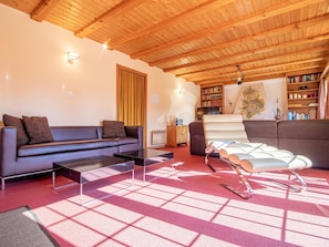 A cozy living room with a wooden ceiling, a sofa, a coffee table, and a patterned rug. - Chalet Soldanella by Arosa Holiday Appartement/Fewo, Dusche oder Bad, WC, 9-Bett by Interhome (Arosa)