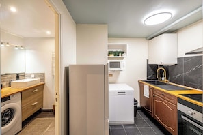 A compact kitchen with a washing machine, a microwave, a sink, and a stove. - Warm Apartment a/c 2br/6p - Nice (Nice)