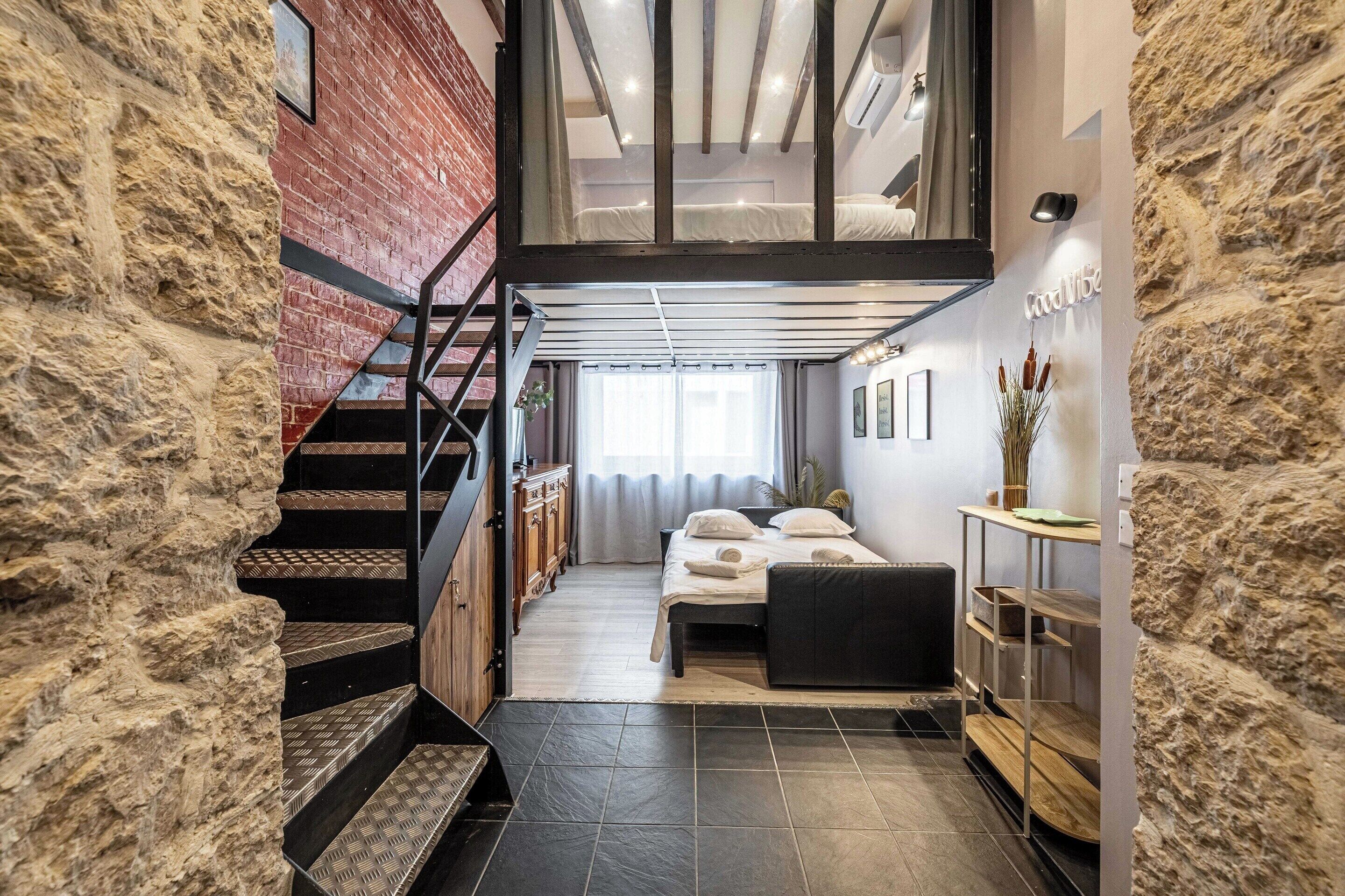 A modern interior with a staircase, a bed, and a desk area.