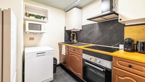 A compact kitchen with a dishwasher, microwave, stove, and a coffee maker on the counter. - Warm Apartment a/c 2br/6p - Nice (Nice)