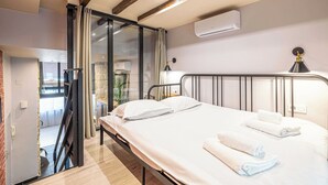 A hotel room with a bed, a desk, a chair, a window, and an air conditioning unit. - Warm Apartment a/c 2br/6p - Nice (Nice)