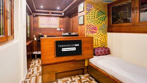 A room with a bed, a reception desk labeled 'TOWNHOUSE OAK,' and a patterned wall. - Suite Room With Ganga View Heritage Scindia Ghat (Varanasi)