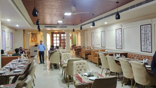 A restaurant with multiple dining tables, chairs, and a person walking.