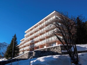 A multi-story hotel with balconies, a stone base, and snow on the ground. - Utoring Hohe Promenade 004 Appartement/Fewo, Dusche, WC, 2-Bettwohnung by Interhome (Arosa)