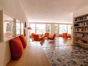 A spacious living area with a wooden floor, orange chairs, a bookshelf, and large windows. - Utoring Hohe Promenade 004 Appartement/Fewo, Dusche, WC, 2-Bettwohnung by Interhome (Arosa)