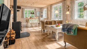 Un salon chaleureux avec une cheminée, un plancher en bois et de grandes fenêtres.