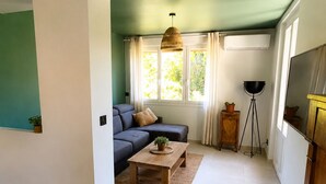 Ett vardagsrum med en soffa, ett soffbord, en golvlampa och ett fönster med gardiner.