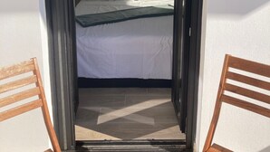 Un dormitorio con cama, almohadas, un cuadro enmarcado y un pequeño letrero triangular en la pared.