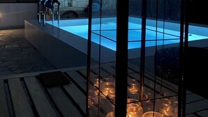 Una piscina con cerramiento de vidrio, rodeada por una terraza de madera.