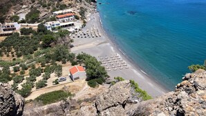 Un hotel frente al mar con playa, terreno rocoso y aguas azul turquesa.