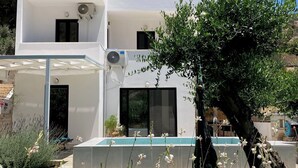 Una casa moderna de dos plantas con techo plano, paneles solares y una piscina.